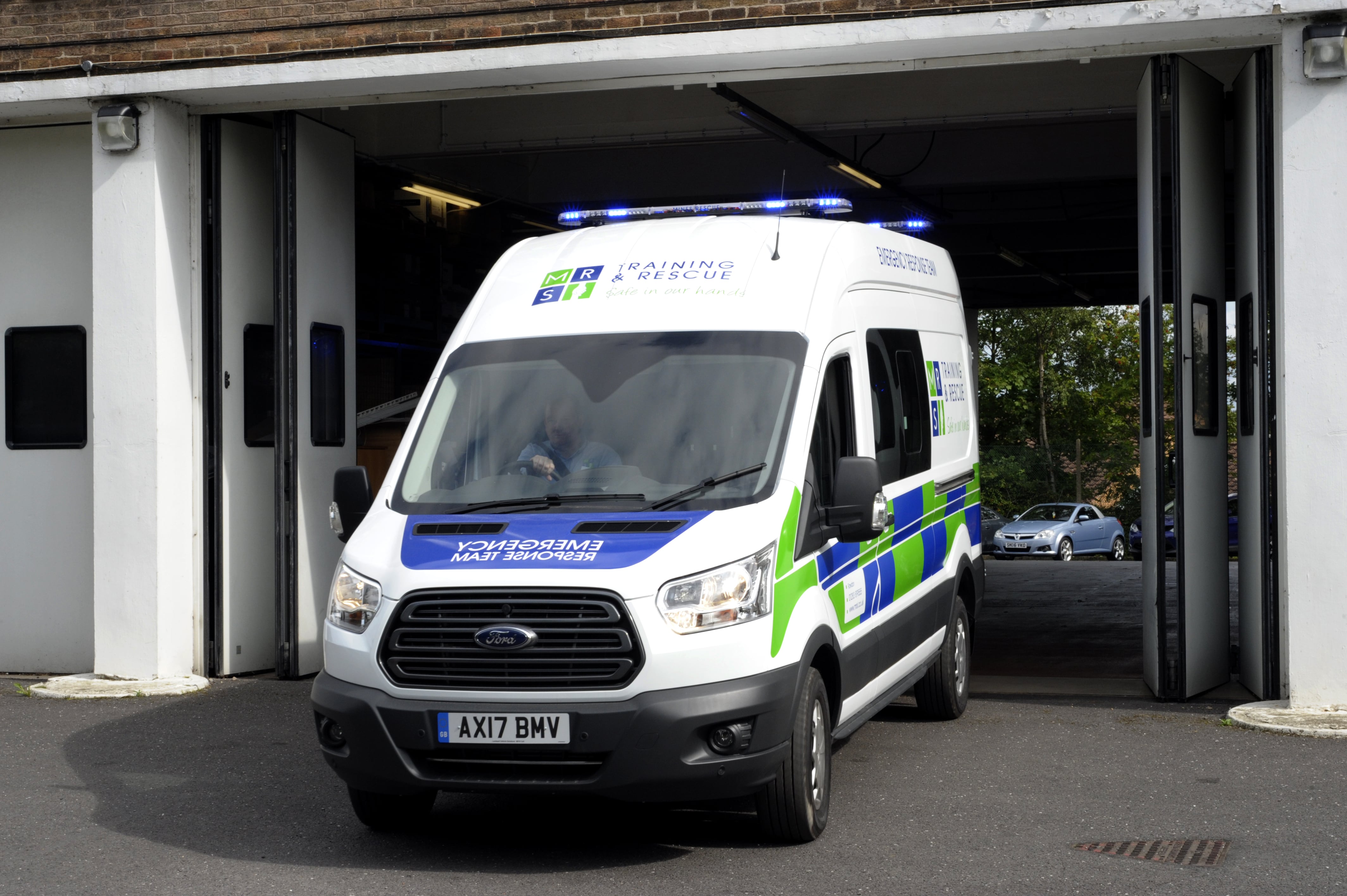 An MRS Training & Rescue specialist van - with blue lights coming our of a garage