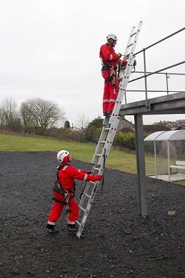 A man holding a ladder and one climbing a ladder, on a Ladder Safety Training course