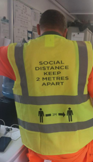 A man wearing a COVID-19 social distancing high visibility safety vest 