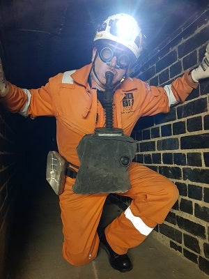 A man in PPE, inside a tunnel - using breathing apparatus 