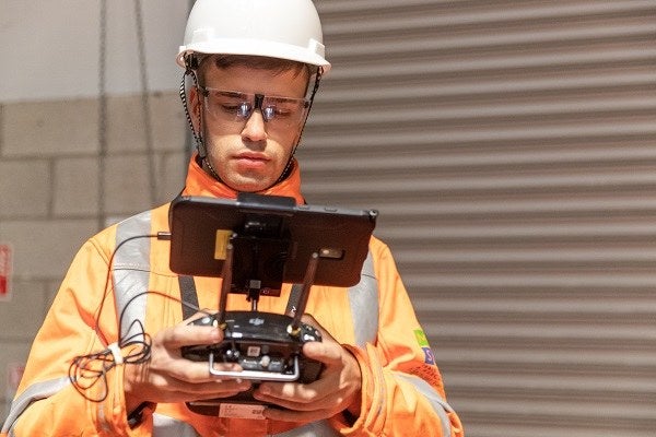 Drone pilot in a hard hat using controls indoors 