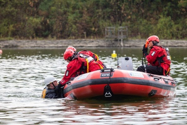 3 Water Rescue operatives rescuing a casualty in water, from a boat 