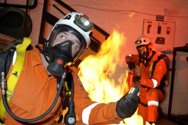 Two men completing high risk confined space training by putting out a fire in a confined space and using breathing apparatus 