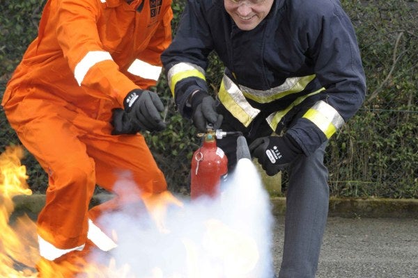 Two men using a portable fire extinguisher 