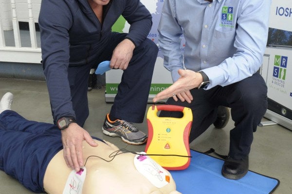 A trainer showing someone how to carry out first aid on a resuscitation dummy.