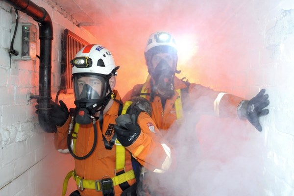 Two men in a confined space filled with gas using breathing apparatus 