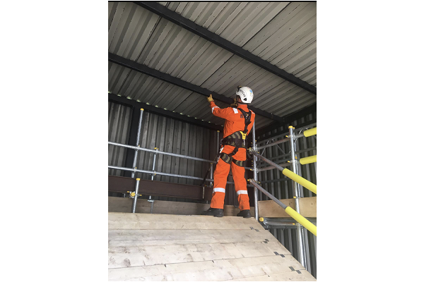 A man is participating in Working Safely at Height training by climbing scaffold