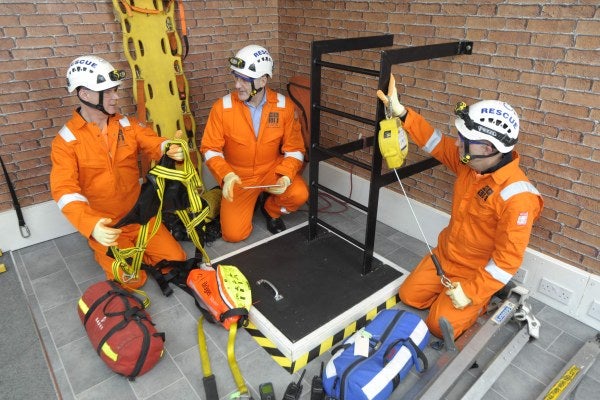 Three men in orange overall carrying out confined space training