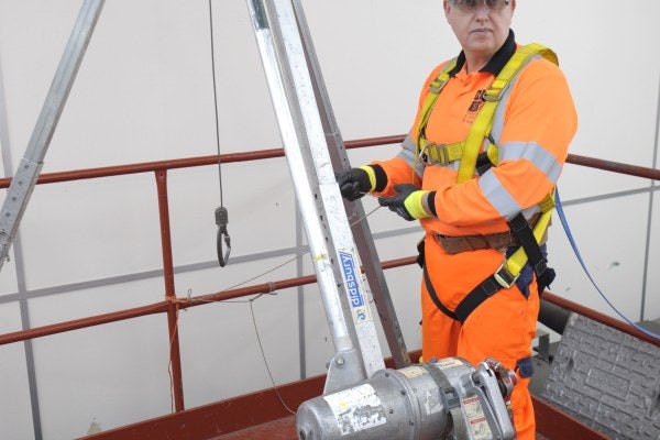 A man in protective clothing demonstrating how to use a winch