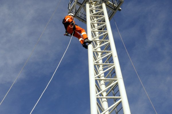 Man in orange suit climbing a tower demonstrating working at heights