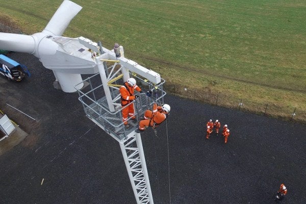 A man in orange overalls is working on a wind turbine, as part of the MRS Advanced Working & Rescue from Height Training Course.