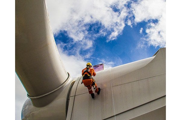 A person using a harness and rope on a wind turbine 