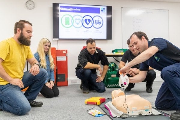 A trainer showing delegates how to perform CPR using a defibrillator