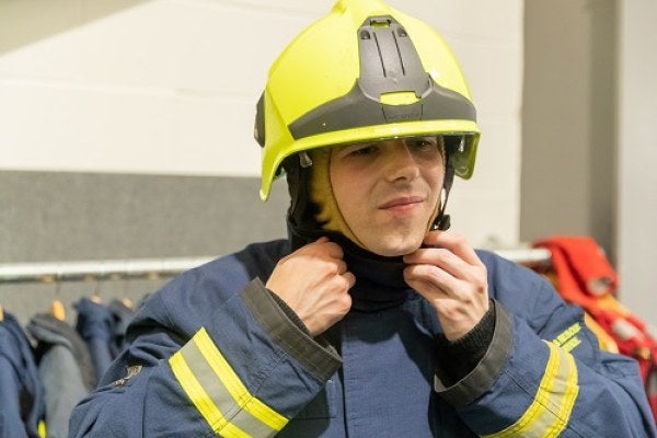 A person donning PPE ahead of practical fire training exercises