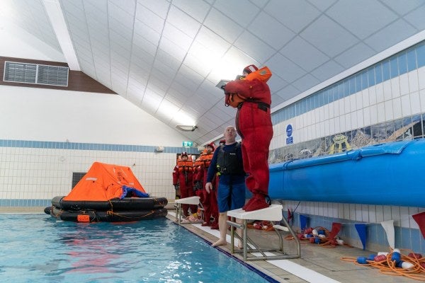 A person stood at the edge of an indoor pool during a how to enter water training session