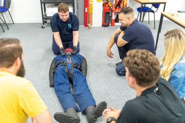 A group training around a mannequin during an Elementary First Aid (EFA) course