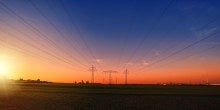 Power lines in a field, at sunset 