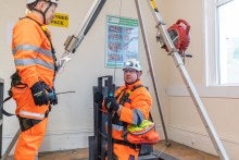 Two rescue operatives using tripod and winch equipment