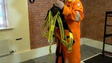 A man fitting a full body safety harness 