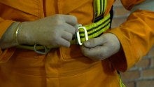 A close up of someone doing up a safety harness